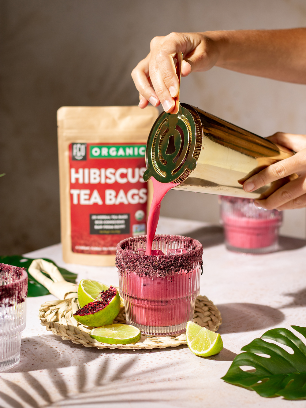 Hibiscus coconut margarita poured from a shaker into a cocktail glass of ice.