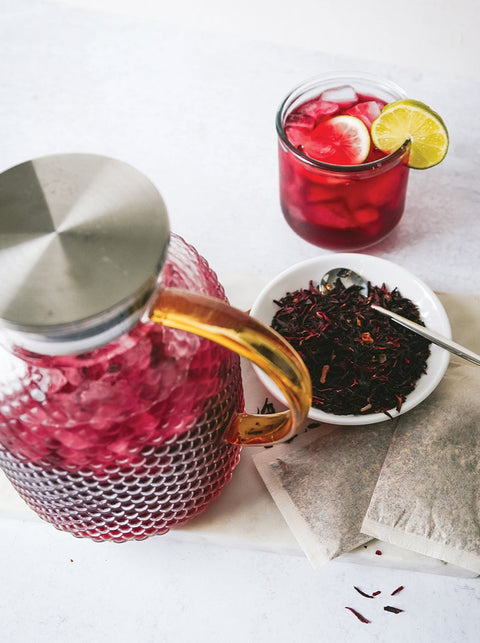 Dried hibiscus flowers and a pitcher of hibiscus iced tea.