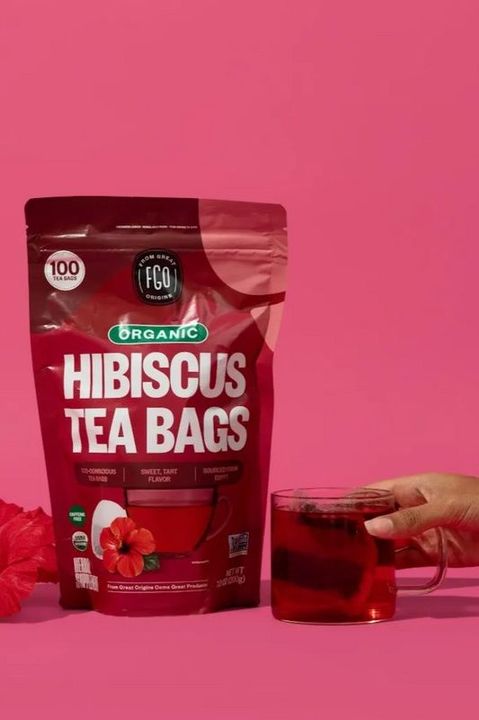 A hand holding a pouch of Hibiscus Tea Bags