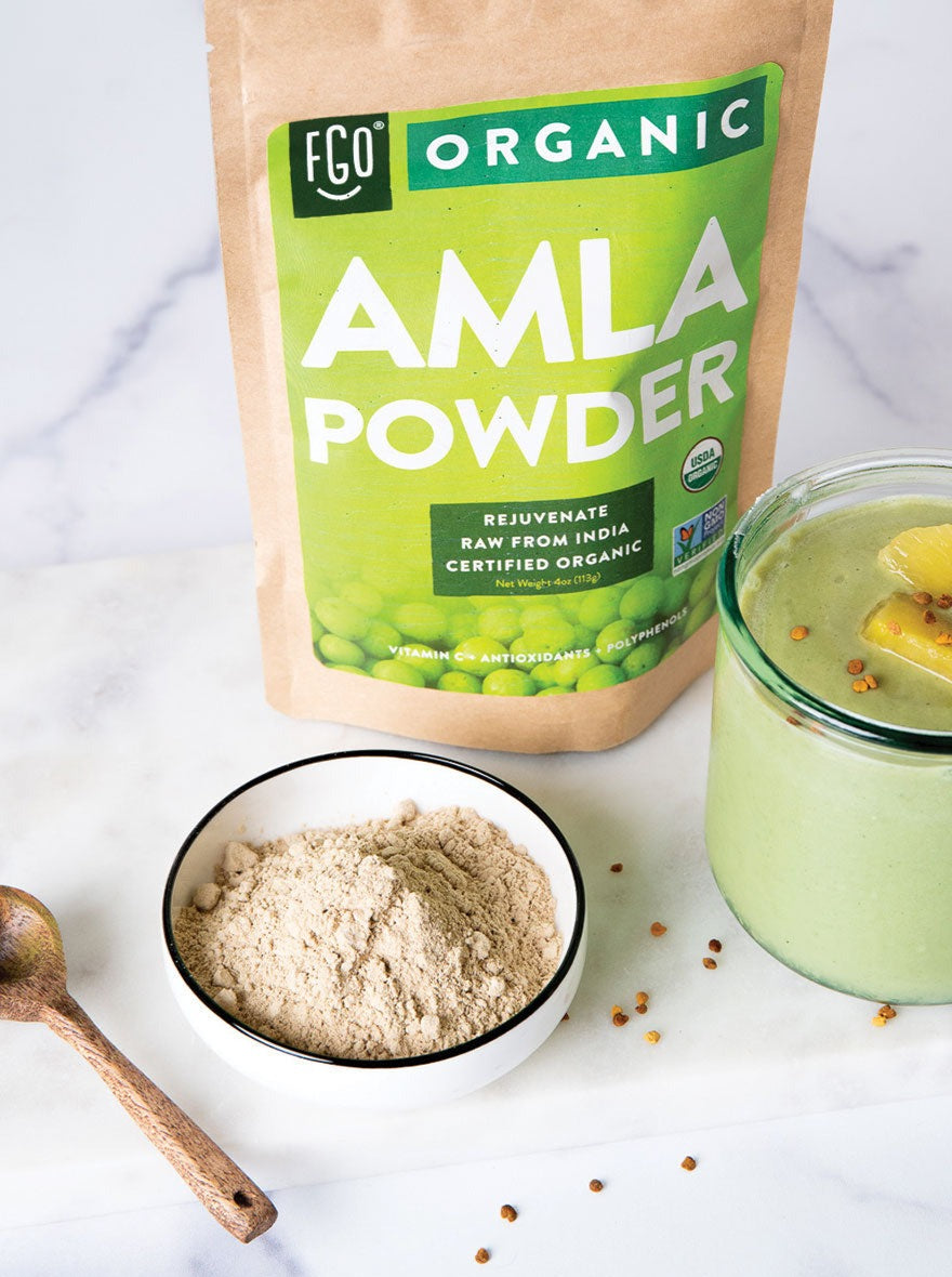 A wooden spoon and bowl of raw amla powder.