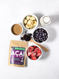 Ingredients for a frozen acai bowl including almond butter, frozen bananas, blueberries, strawberries, and almond milk.