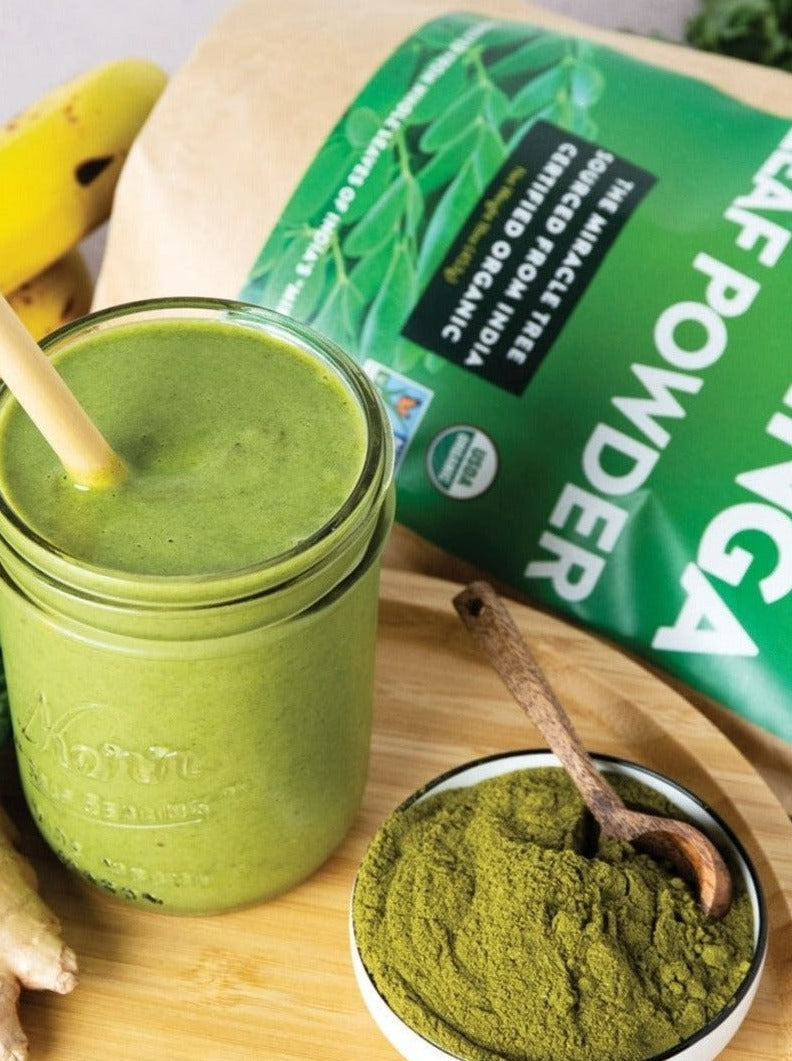 Moringa leaf powder in a wooden spoon.