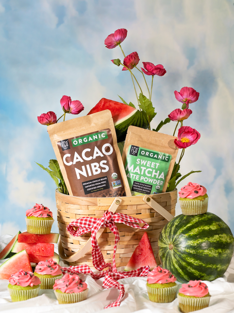 Sweet watermelon matcha cupcakes in a basket full of fresh watermelon and cacao nibs.