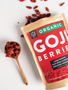 Raw goji berries in a wooden spoon spilled on the counter.