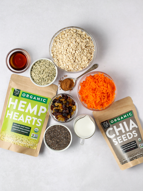 Ingredients for carrot cake chia seed pudding: hemp heart seeds, chia seeds, shredded carrots, and almond milk.