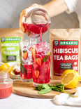 Hibiscus mint tea poured into a glass of ice with fresh strawberries and mint leaves.