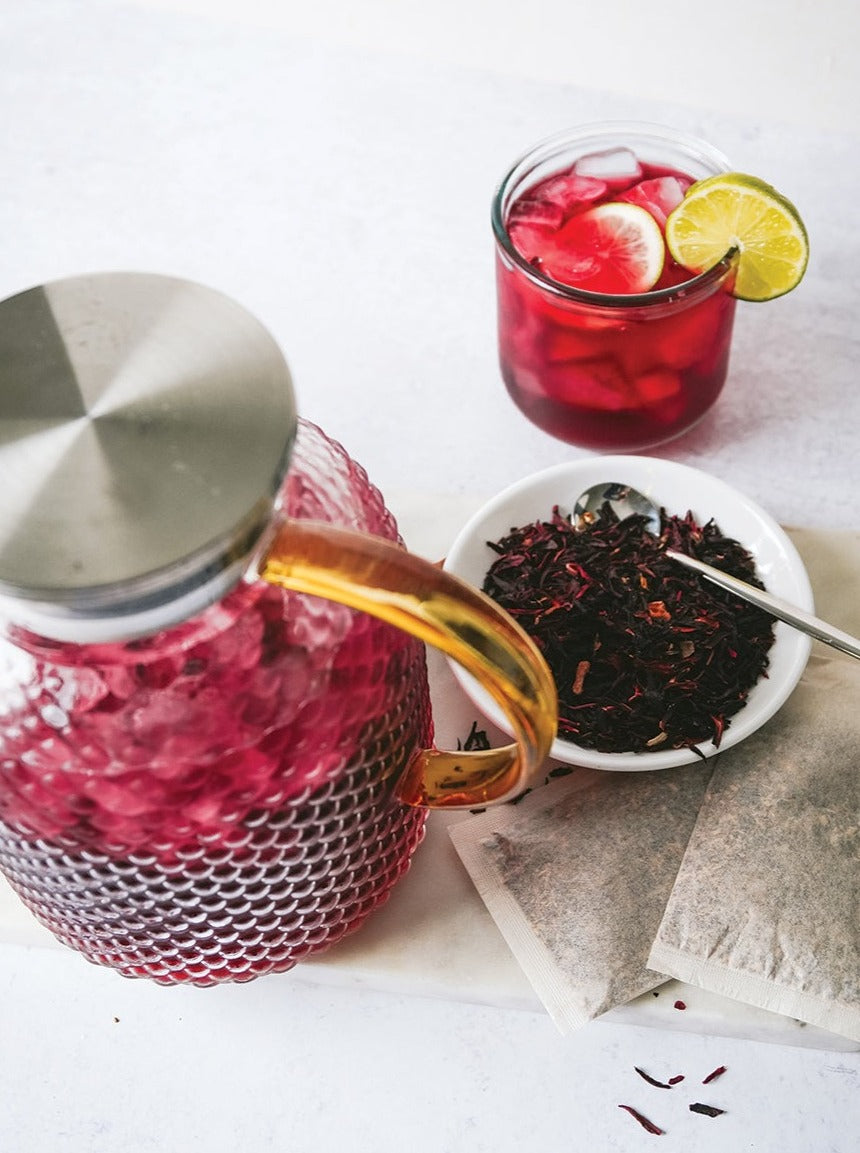 Dried hibiscus flowers and a pitcher of hibiscus iced tea.