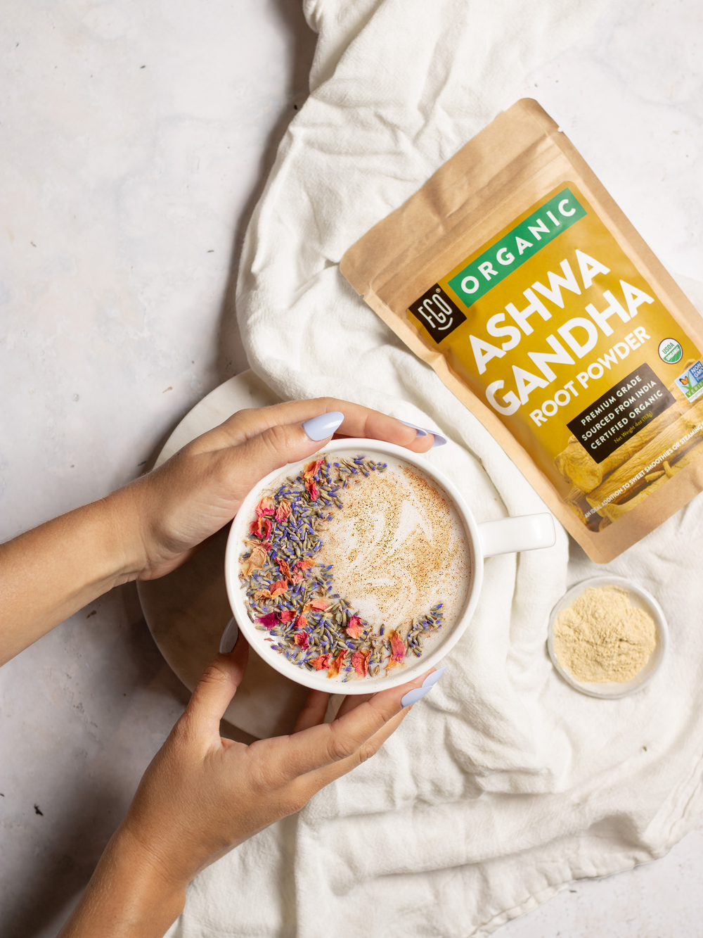 Hands wrapped around a mug of moon milk made with ashwagandha root powder.