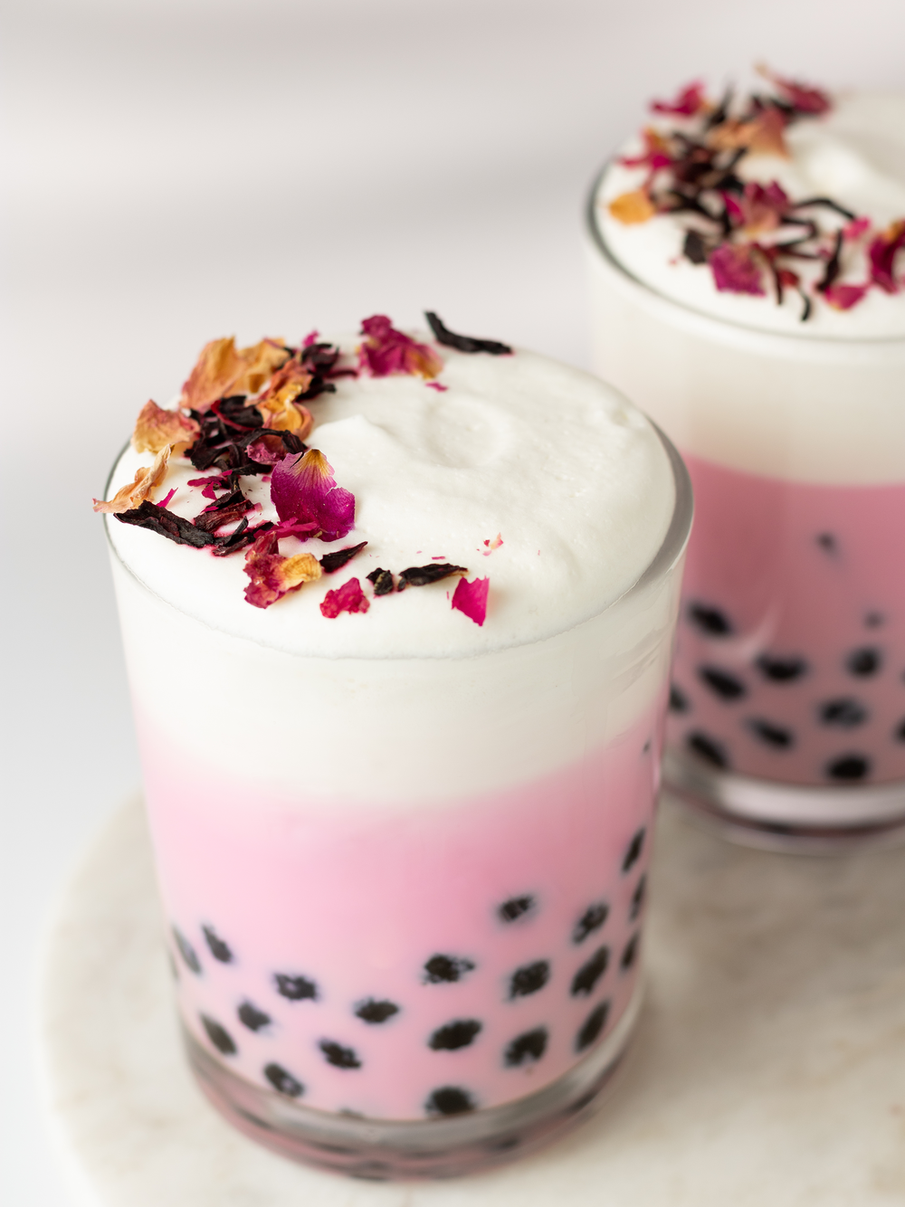 A frothy hibiscus boba tea latte topped with rose hips.