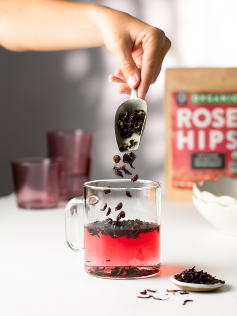 Cut and sifted rose hips poured into a glass of hot hibiscus tea.