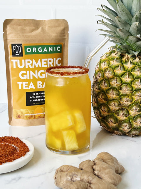 Iced Pineapple Turmeric Ginger Tea with fresh pineapples and a Tajin rim.