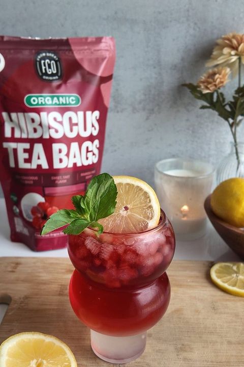 A tall glass of iced hibiscus tea beside the pouch