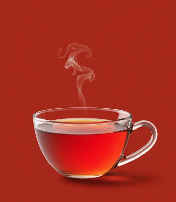 A steaming glass cup of red tea on a deep red ground