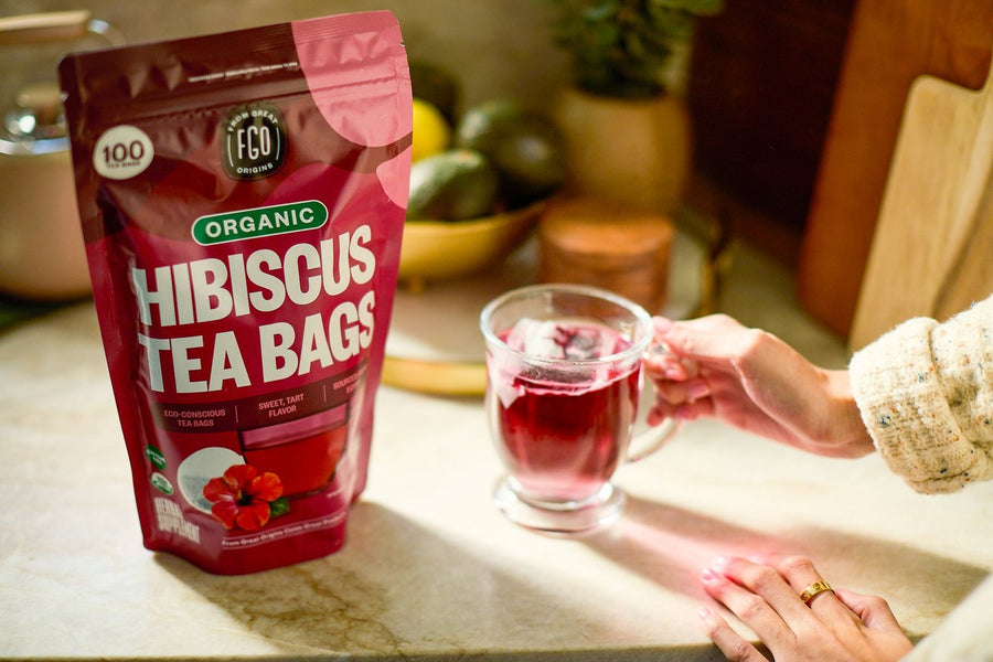 A Hibiscus Tea Bags pack on a kitchen counter beside a glass mug of hibiscus tea