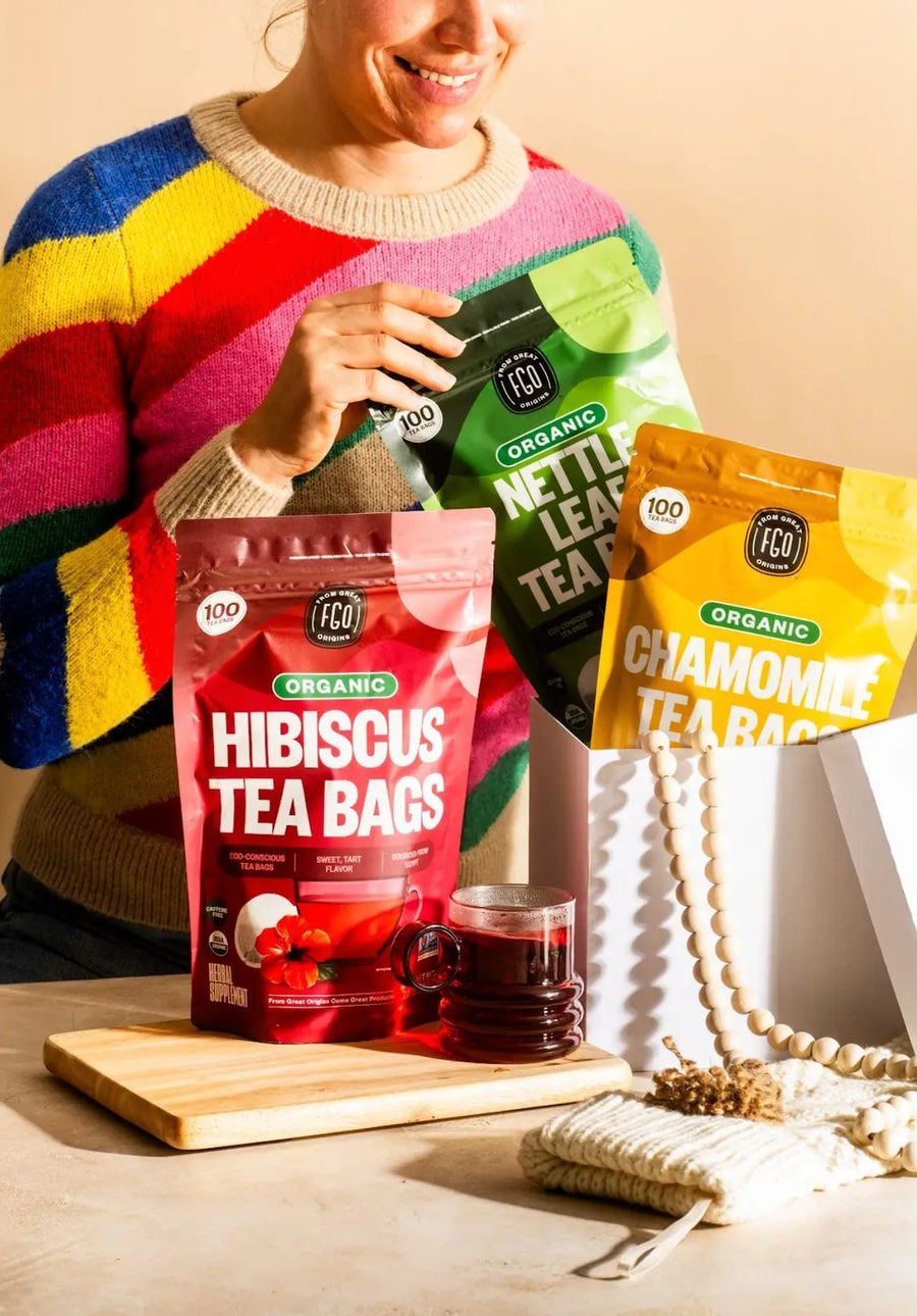 A woman unboxing packs of Nettle Leaf and Chamomile tea bags