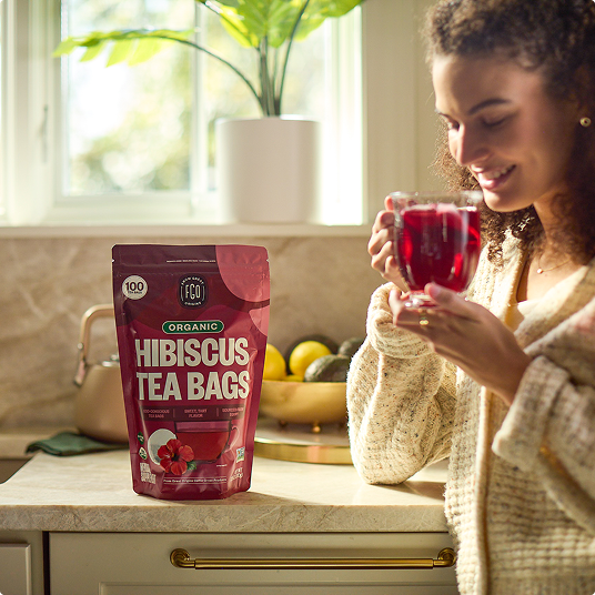 A customer holding a glass mug of brewed hibiscus tea